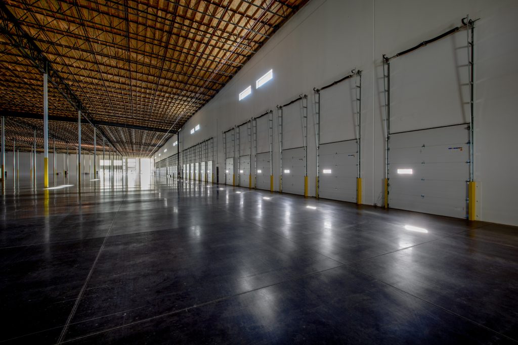 Empty warehouse with vanishing point perspective featuring a row of commercial garage doors